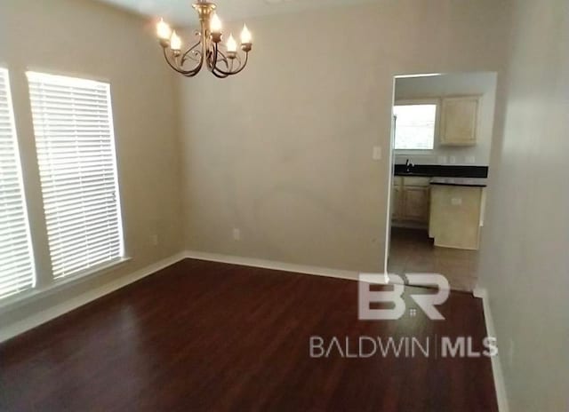 unfurnished room with sink, hardwood / wood-style floors, and an inviting chandelier