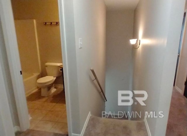 bathroom featuring washtub / shower combination, tile patterned floors, and toilet