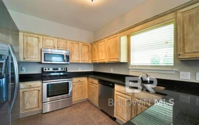 kitchen with sink, stainless steel appliances, dark tile patterned flooring, and a wealth of natural light