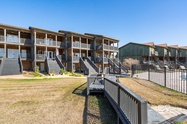 view of home's community featuring fence, stairway, and a lawn