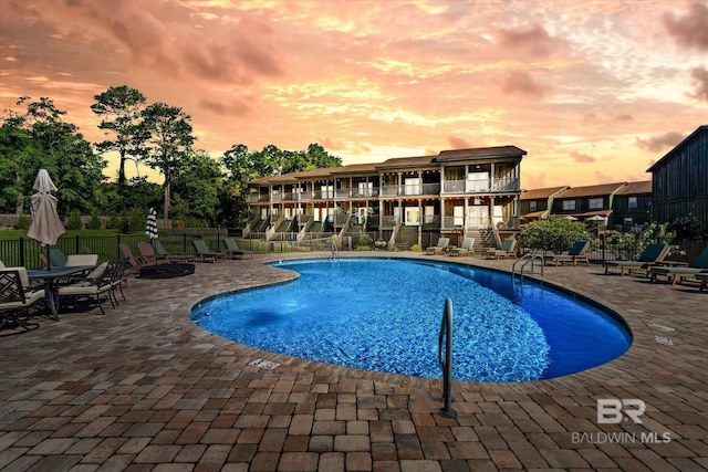 community pool with a patio area and fence