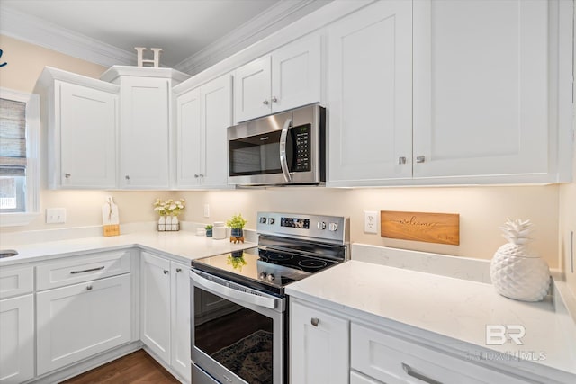 kitchen featuring dark wood finished floors, white cabinets, light stone counters, appliances with stainless steel finishes, and crown molding