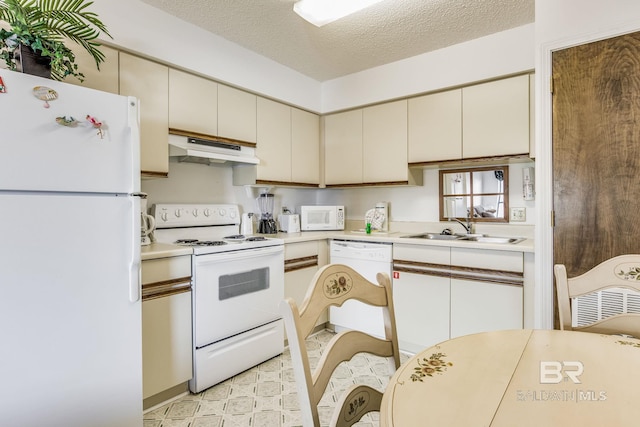 kitchen featuring sink, cream cabinetry, white appliances, and a textured ceiling