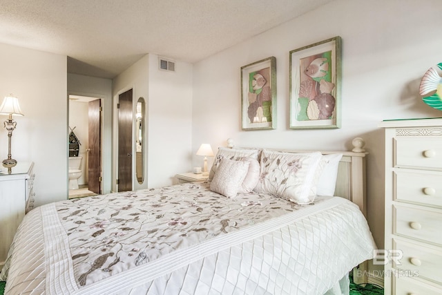 bedroom with a textured ceiling and ensuite bath