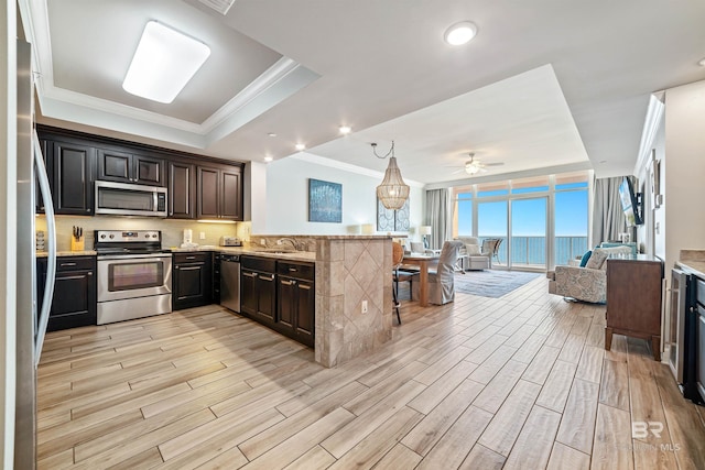 kitchen with appliances with stainless steel finishes, open floor plan, expansive windows, crown molding, and wood finish floors