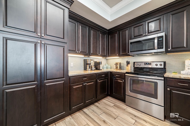 kitchen featuring crown molding, stainless steel appliances, light wood-style flooring, decorative backsplash, and light stone countertops