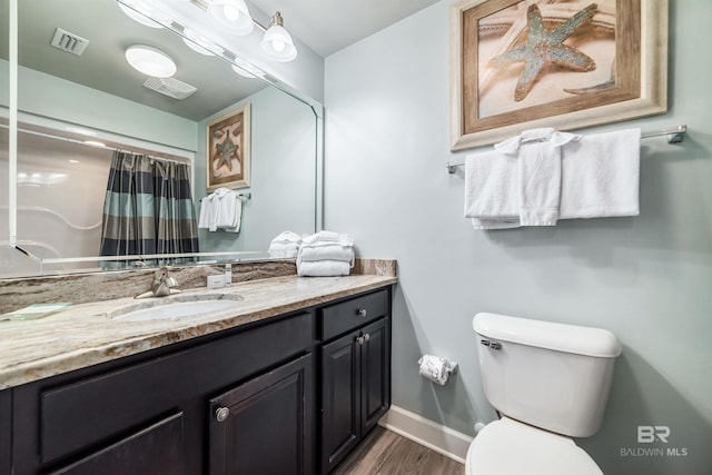 bathroom with visible vents, toilet, vanity, wood finished floors, and baseboards