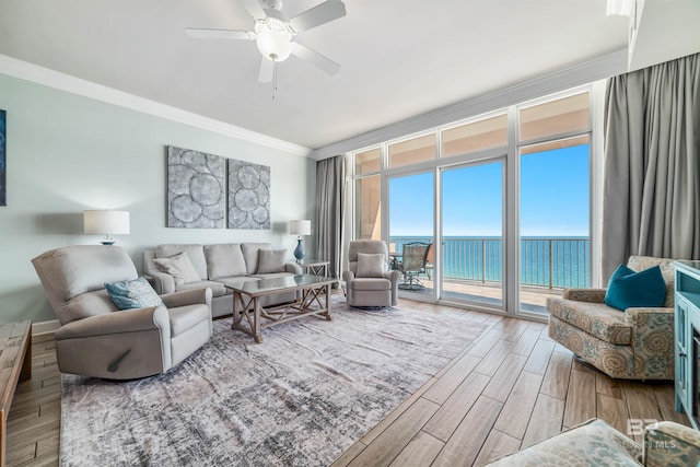 living area featuring ceiling fan, wood finished floors, a water view, crown molding, and floor to ceiling windows