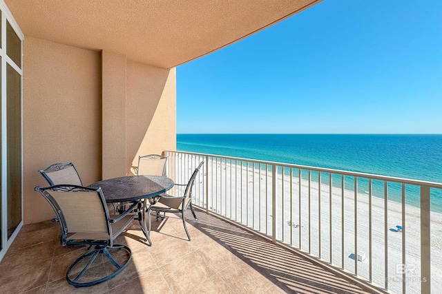 balcony featuring a view of the beach and a water view