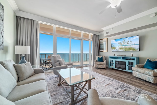 living area featuring ceiling fan, floor to ceiling windows, crown molding, and wood finished floors