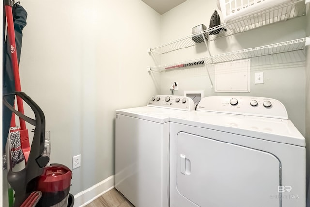 laundry room featuring laundry area, washing machine and clothes dryer, light wood-style flooring, and baseboards