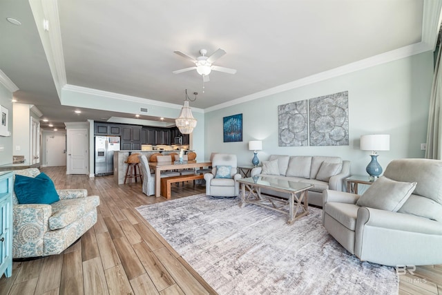 living area featuring ornamental molding, light wood-type flooring, and a ceiling fan