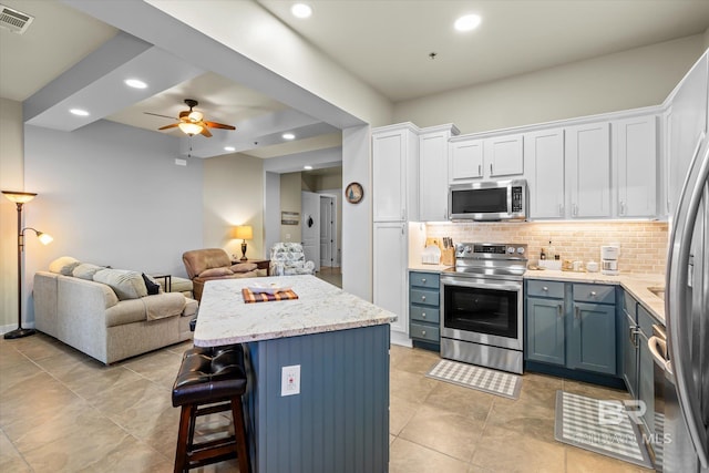 kitchen featuring a kitchen island, white cabinetry, appliances with stainless steel finishes, and backsplash