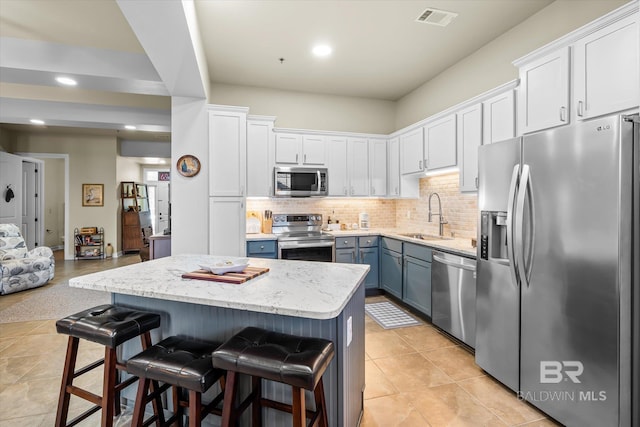 kitchen featuring sink, a breakfast bar, appliances with stainless steel finishes, white cabinetry, and a center island