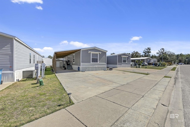 view of front of property featuring central air condition unit, concrete driveway, a residential view, a carport, and a front yard