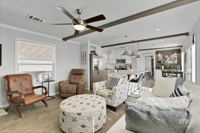 living area with beam ceiling, light wood finished floors, recessed lighting, visible vents, and baseboards