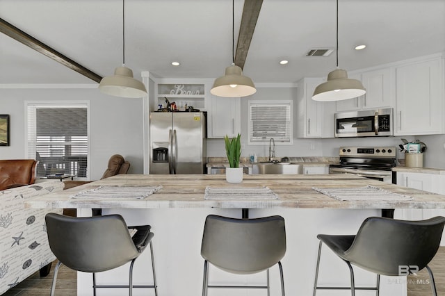 kitchen featuring visible vents, white cabinets, a kitchen island, appliances with stainless steel finishes, and pendant lighting