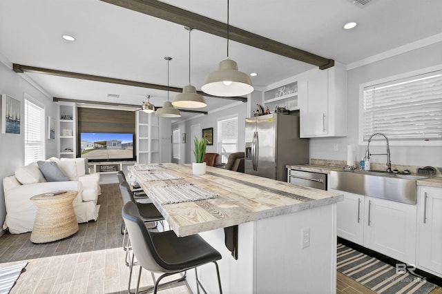 kitchen with pendant lighting, appliances with stainless steel finishes, a sink, and white cabinets