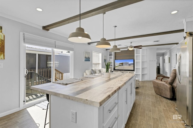 kitchen with freestanding refrigerator, white cabinetry, pendant lighting, and open floor plan