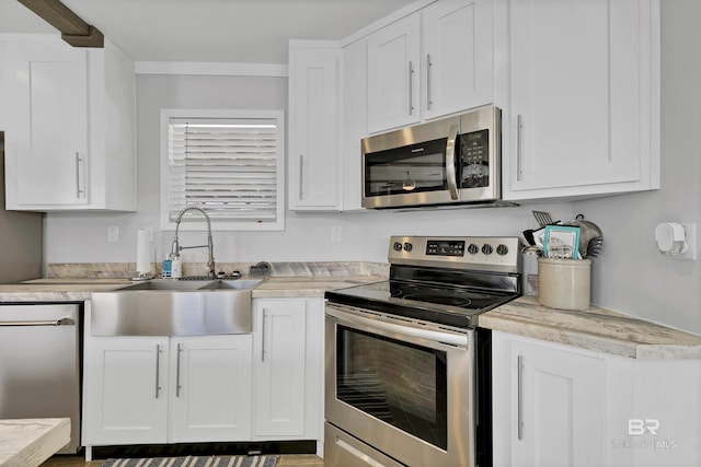 kitchen featuring stainless steel appliances, light countertops, a sink, and white cabinetry