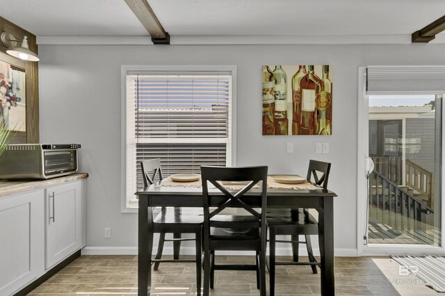 dining room featuring wood tiled floor, beam ceiling, and baseboards