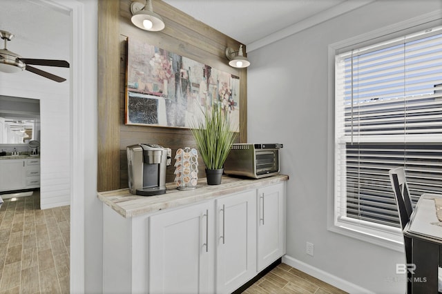 bar featuring ceiling fan, wood finish floors, a sink, and a toaster