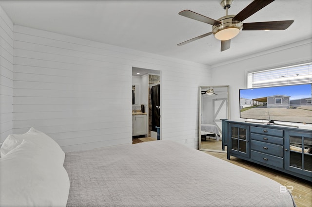 bedroom with ceiling fan, wood walls, and light wood-type flooring