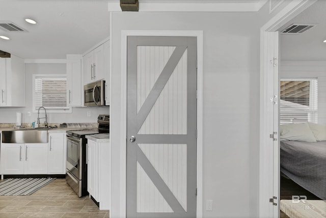 kitchen featuring stainless steel appliances, a sink, visible vents, white cabinets, and light countertops