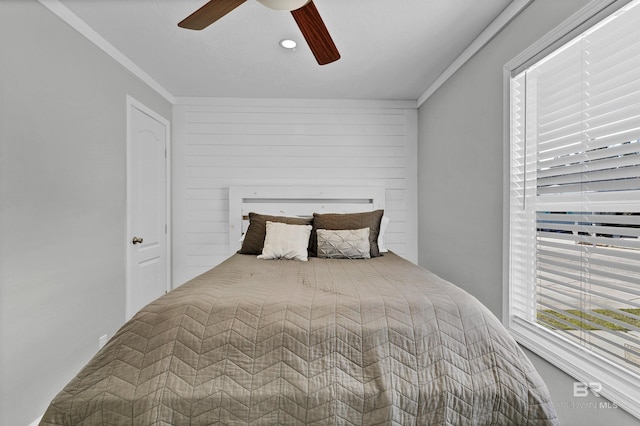 bedroom with ceiling fan, wood walls, and crown molding