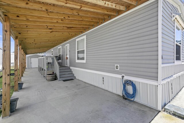 view of home's exterior with a storage unit, a patio, and an outbuilding