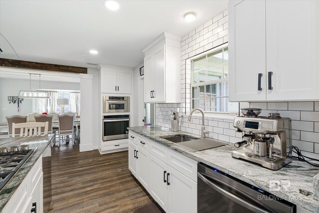 kitchen with dark hardwood / wood-style floors, sink, white cabinetry, appliances with stainless steel finishes, and light stone countertops