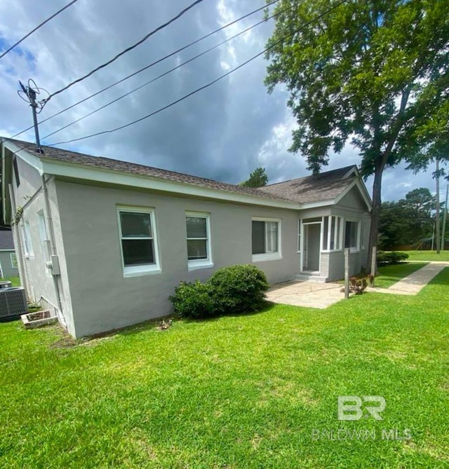 view of front of home with a patio, central air condition unit, and a front lawn