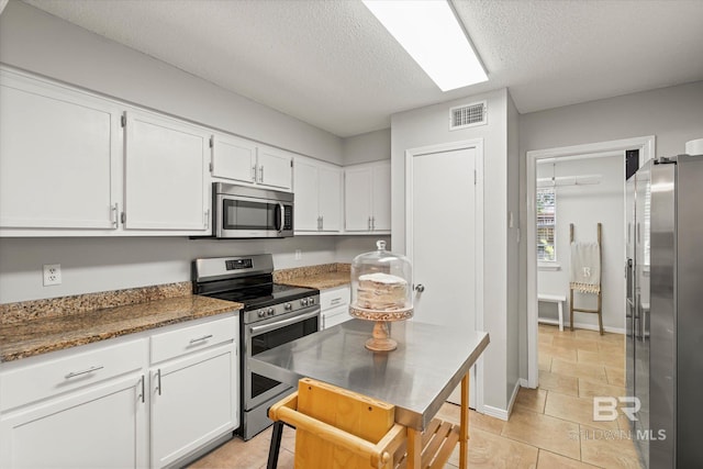 1116 Linlen Ave, Mobile, AL 36609 - kitchen with appliances with stainless steel finishes, white cabinets, a textured ceiling, dark stone countertops, and baseboards
