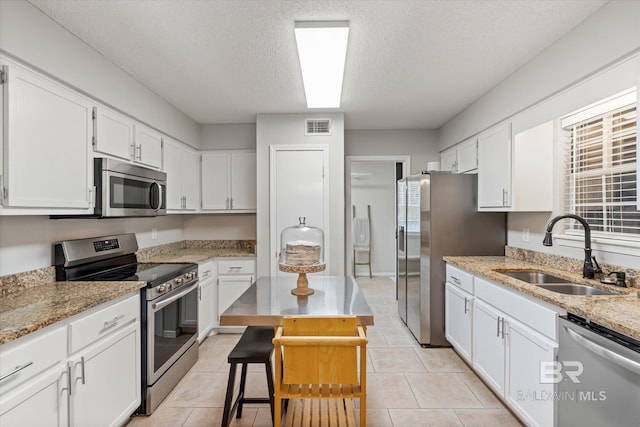1116 Linlen Ave, Mobile, AL 36609 - kitchen with appliances with stainless steel finishes, a sink, a textured ceiling, white cabinetry, and light stone counters
