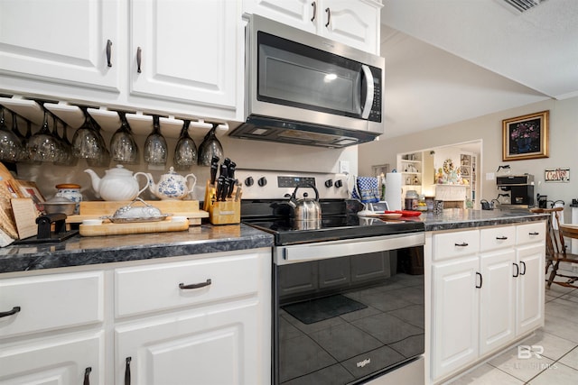 kitchen featuring dark countertops, light tile patterned floors, white cabinets, and stainless steel appliances