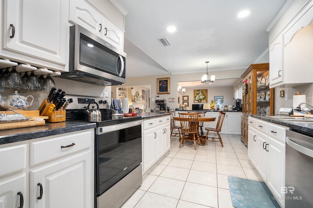 kitchen featuring stainless steel appliances, dark countertops, light tile patterned flooring, and a notable chandelier