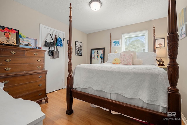 bedroom featuring light wood finished floors and a textured ceiling