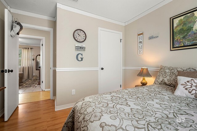 bedroom featuring baseboards, ornamental molding, and light wood finished floors