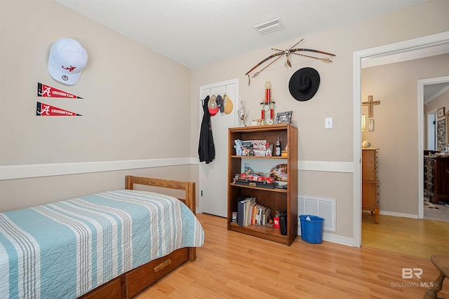 bedroom featuring visible vents, baseboards, and wood finished floors