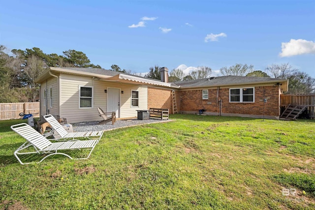 back of house with brick siding, fence, a chimney, a yard, and a patio area