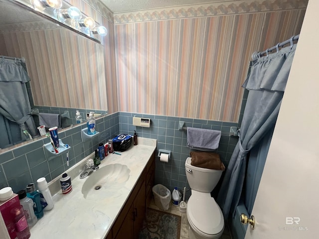 bathroom featuring vanity, a shower with curtain, toilet, a textured ceiling, and tile walls