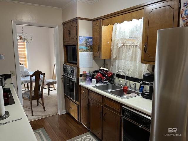 kitchen featuring dark wood-type flooring, black appliances, sink, ornamental molding, and a notable chandelier