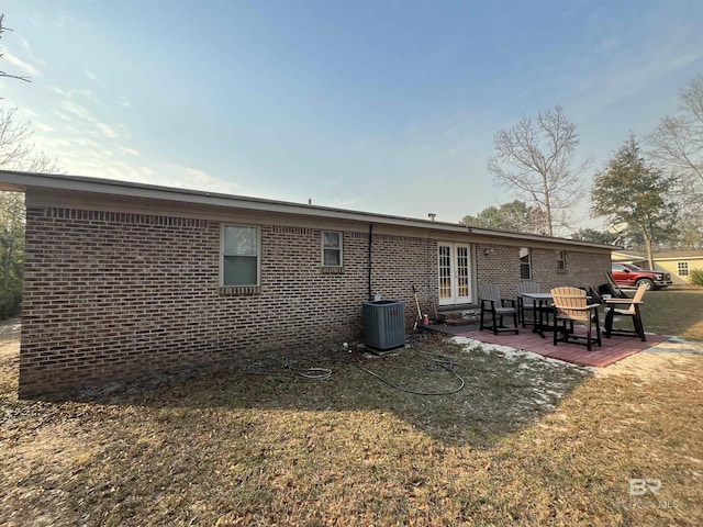 rear view of house featuring a lawn, cooling unit, a patio, and french doors