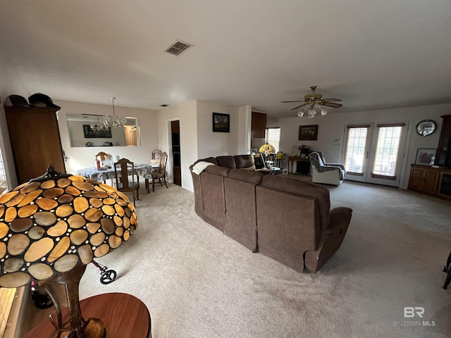 carpeted living room with ceiling fan with notable chandelier