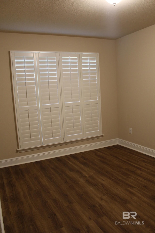 interior space with a textured ceiling, dark wood-style flooring, and baseboards