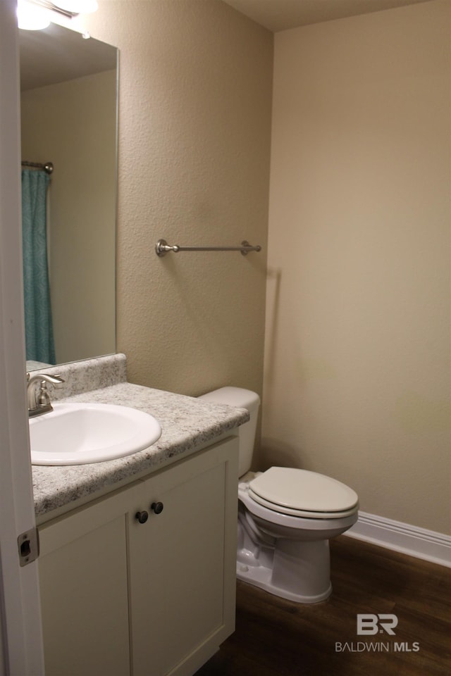 full bath with baseboards, vanity, toilet, and wood finished floors