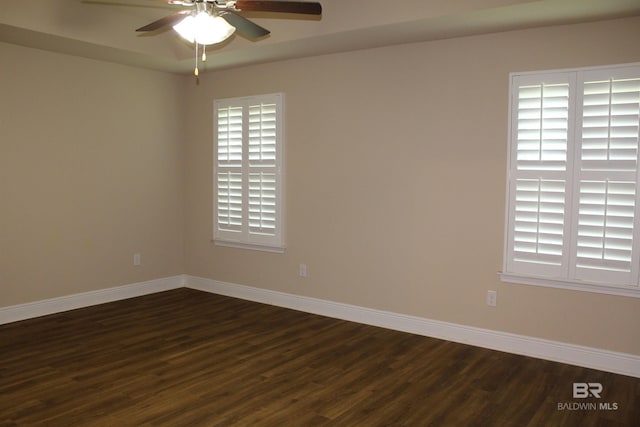 spare room with dark wood-style floors, baseboards, and a ceiling fan