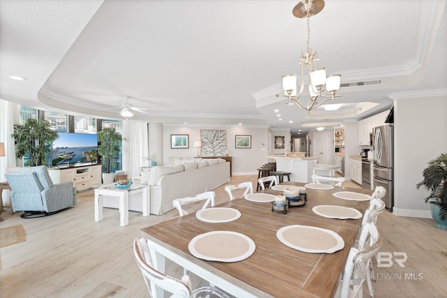 dining room with light wood finished floors, visible vents, a raised ceiling, crown molding, and ceiling fan with notable chandelier