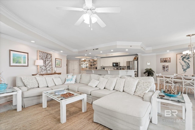 living room with ceiling fan with notable chandelier, a tray ceiling, crown molding, and recessed lighting