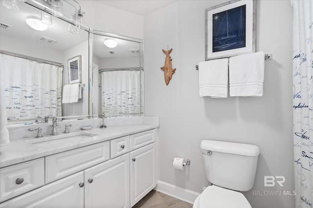 full bathroom featuring a textured ceiling, toilet, vanity, visible vents, and baseboards